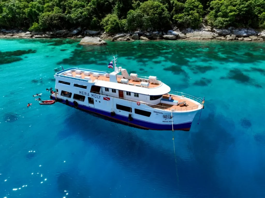 Dive boat anchored near a tropical island in Phuket with snorkelers in the water