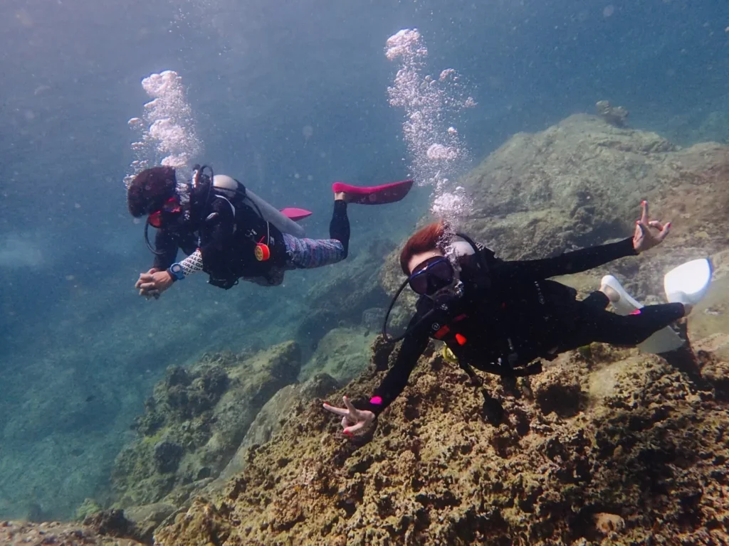 Two divers enjoying fun diving over a rocky reef in Phuket