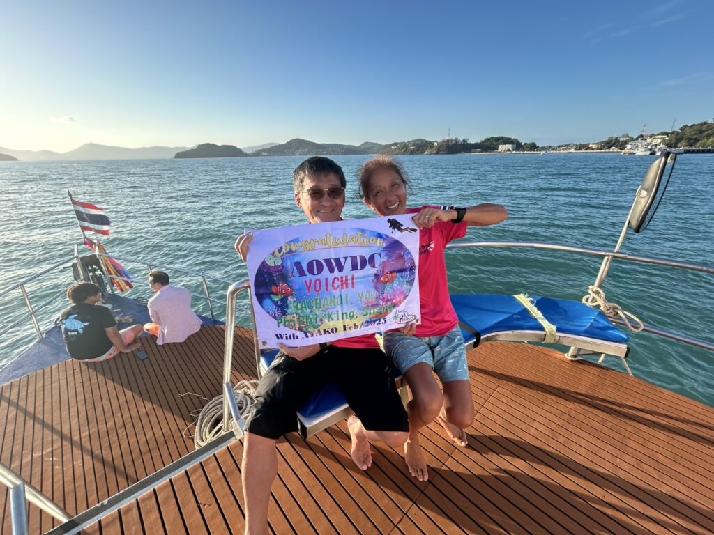Diving students celebrating after completing a PADI course on a boat in Phuket
