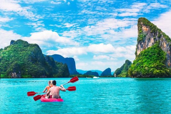 Couple kayaking through the limestone cliffs of Phang Nga Bay, Thailand