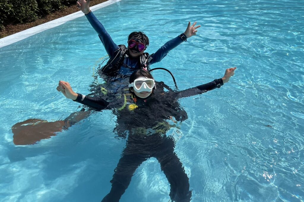 プールで浮上練習をしながらポーズを取るダイバー