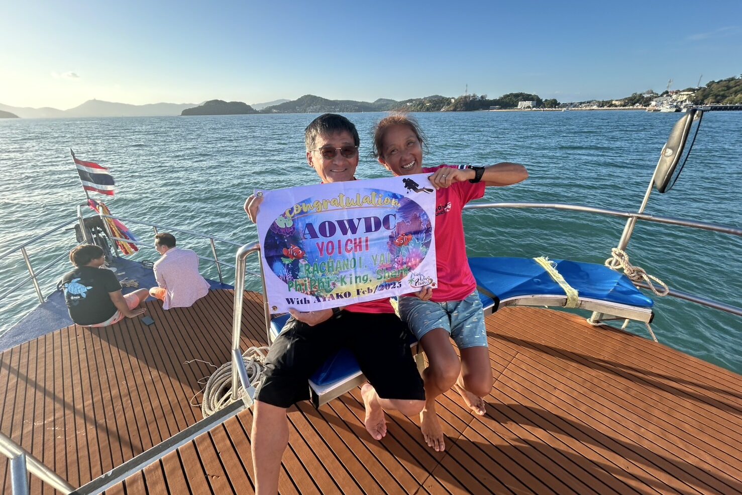 Diving students celebrating after completing a PADI course on a boat in Phuket