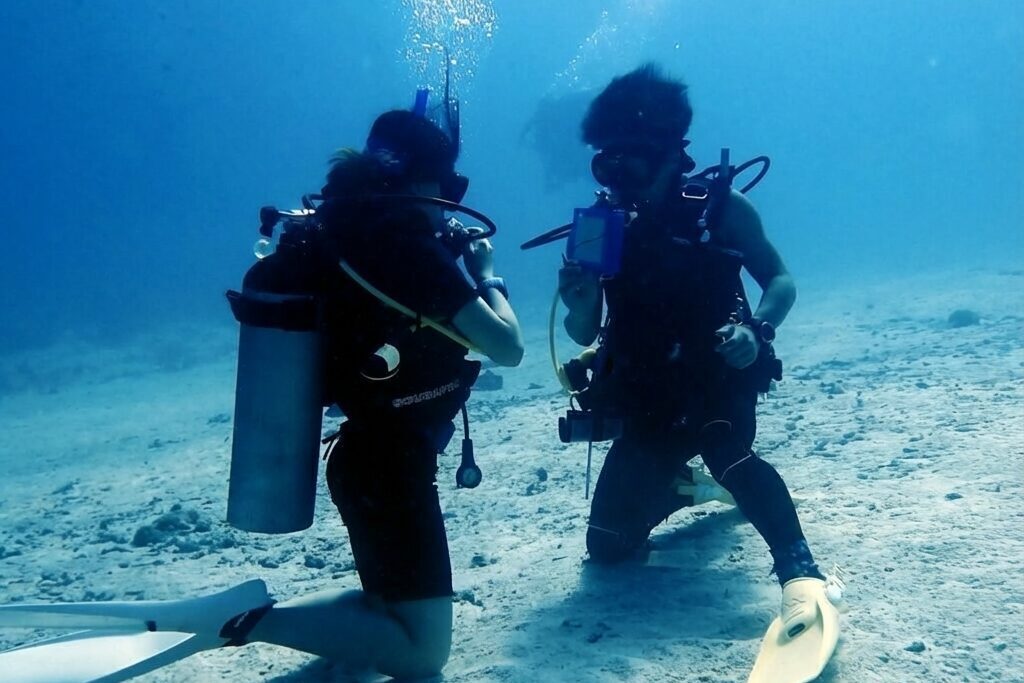 海底で向かい合ってスキル練習をするダイバー